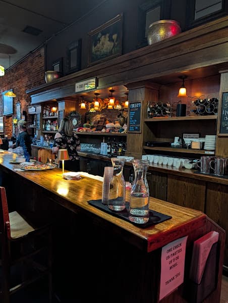 The long wood bar at Vintage Cafe under a row of Tiffany pendant lamps