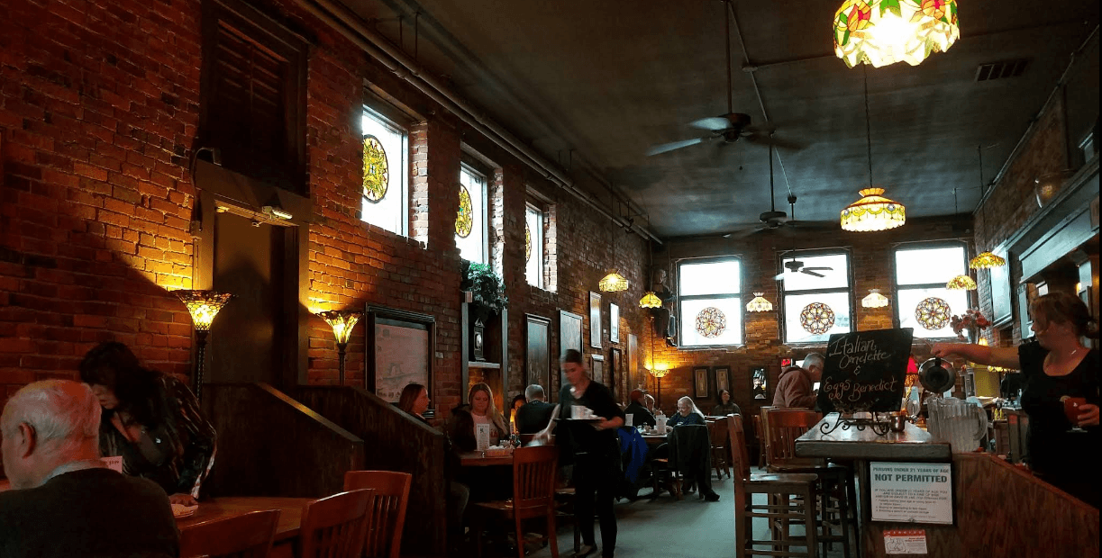 The busy brick-walled dining room at Vintage Cafe, with stained-glass windows, Tiffany pendant lamps, and diners at their tables